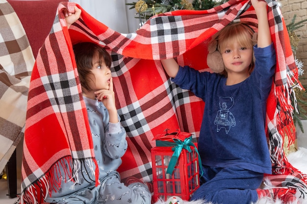 Vorderansicht kleine süße Jungs, die sich mit kariertem Laken verstecken