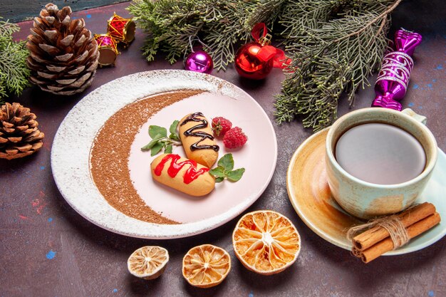 Vorderansicht kleine süße Kekse mit Tasse Tee auf dunklem Raum