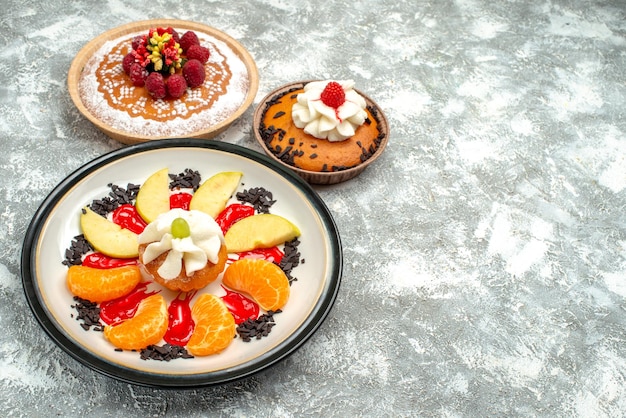 Vorderansicht kleiner Kuchen mit geschnittenen Früchten und Kuchen auf weißem Hintergrund süßer Obstkuchen Cookie Zuckerkeks