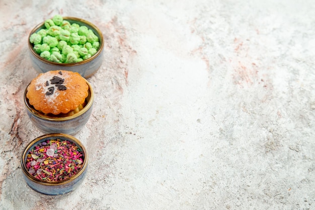 Kostenloses Foto vorderansicht kleiner kuchen mit süßigkeiten auf weißem schreibtisch süßigkeiten kuchen keks