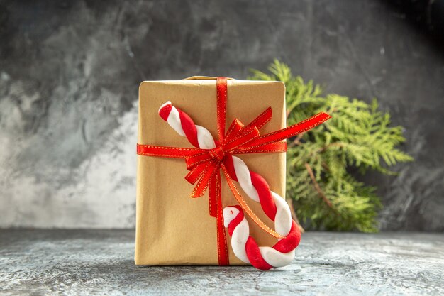 Vorderansicht kleines Geschenk mit rotem Band Weihnachtssüßigkeit Tannenzweig auf Grau gebunden