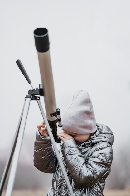 Vorderansicht kleines Mädchen mit einem Teleskop