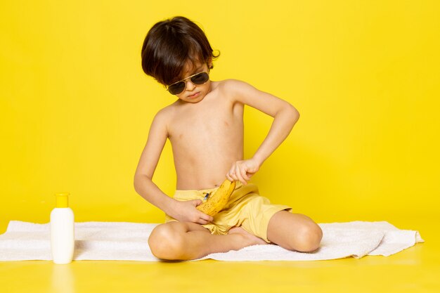 Vorderansicht kleines süßes Kind in der Sonnenbrille auf dem gelben Schreibtisch
