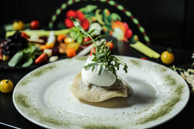 Kostenloses Foto vorderansicht knödel mit saurer sahne und rucola auf einem teller mit gewürzen