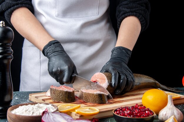 Vorderansicht-Koch, der rohen Fisch auf Schneidebrettmehlschüssel auf Tisch schneidet
