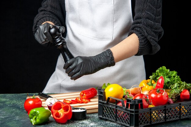 Vorderansicht Köchin, die Gemüse auf dunkler Farbsalatküchenküche würzt