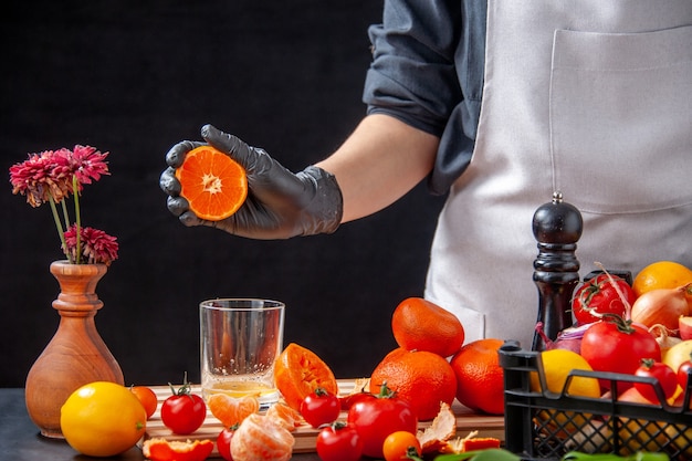 Vorderansicht Köchin, die Mandarinensaft auf dem schwarzen Salat Gesundheit Mahlzeit Lebensmittel Job Diät Gemüse frisches Getränk Obst macht
