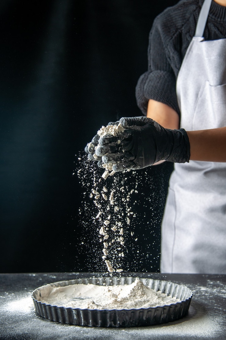 Kostenlose Foto vorderansicht köchin gießt weißes mehl in die pfanne auf dunklem eierkuchen bäckerei gebäck küche kuchen hotcake küchenteig