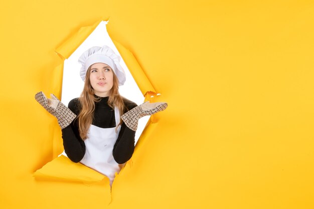 Vorderansicht Köchin in Kochhandschuhen und weißer Kochmütze auf gelber Emotion Lebensmittelfarbe Küche Küchenjob Foto Sonne