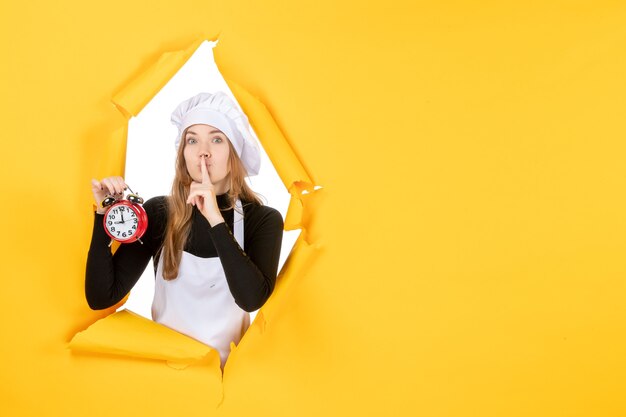 Vorderansicht Köchin in weißer Kochmütze mit Uhr auf gelbem Foto Farbjob Emotion Küche Küche Sonne Essen