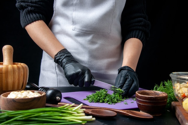 Vorderansicht Köchin macht Gemüsesalat Schneiden von Grüns auf dunklem Hintergrund Küche Urlaub Arbeit Essen Mahlzeit Job Farbe Küche