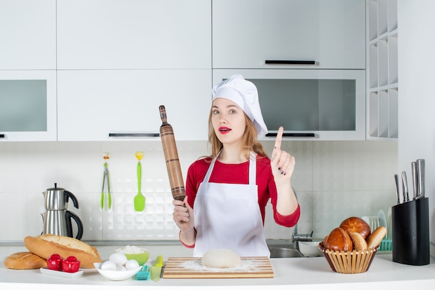 Vorderansicht Köchin mit Nudelholz überraschend mit einer Idee in der Küche