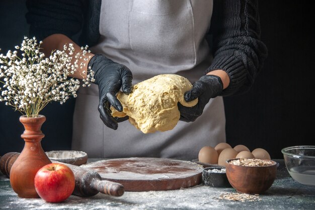 Vorderansicht Köchin rollt Teig auf dem dunklen Job aus roher Teigkuchen Ofen Gebäck Hotcake Bäckerei Ei