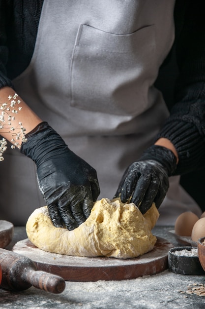 Vorderansicht Köchin rollt Teig auf dunkle Küche Job Gebäck Hotcake Bäckerei Eier Teig aus