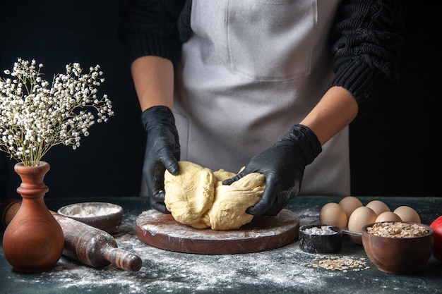 Vorderansicht Köchin rollt Teig auf dunklem Gebäck Job Rohteig Hotcake Bäckerei Kuchen aus