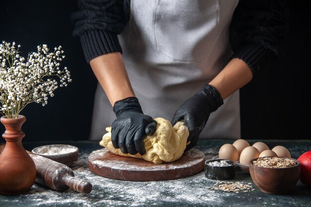 Vorderansicht Köchin rollt Teig auf dunklem Job roher Teig Hotcake Bakery Pie Ofen Gebäck aus