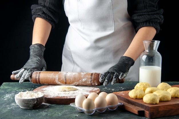 Vorderansicht Köchin rollt Teig mit Mehl auf dunklem Kuchen Job Ofen Hotcake Teig backen Kuchen Arbeiter Eier Küche