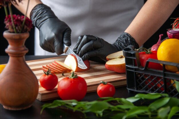 Vorderansicht Köchin schneiden Apfel auf einem dunklen Kochsalat Gesundheit Job Diät Gemüse Essen Essen Obst