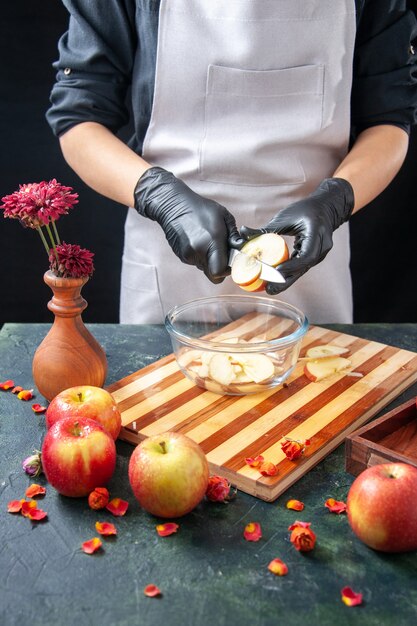 Vorderansicht Köchin schneidet Äpfel in Teller auf dunklem Obst Diät Salat Essen Mahlzeit exotische Saft Arbeit Kuchen Kuchen