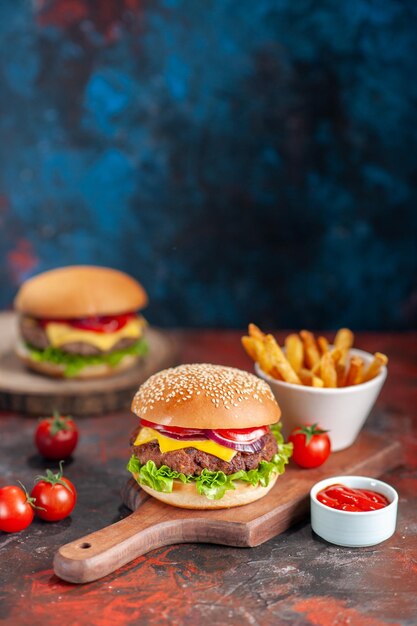 Vorderansicht köstliche Fleisch-Cheeseburger mit Tomaten und Pommes Frites auf dunklem Hintergrund Gericht Fast-Food-Mahlzeit Sandwich Toasts Snack Dinner