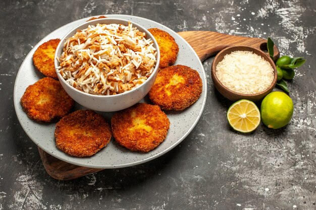 Vorderansicht köstliche gebratene Schnitzel mit gekochtem Reis auf dunklem Oberflächengericht Frikadellenfleisch