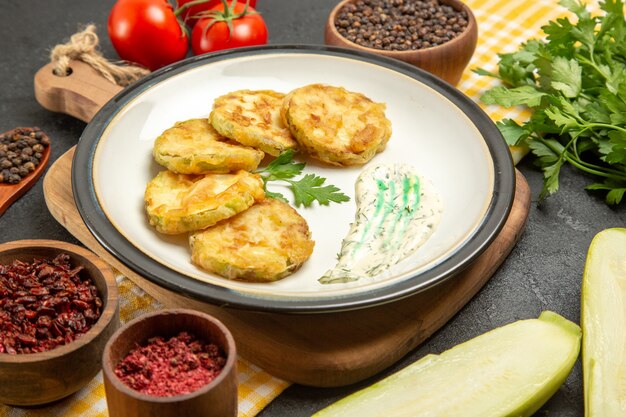 Vorderansicht köstliche gekochte Kürbisse mit Gewürzen und Tomaten auf Grauzone