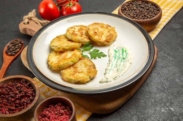 Vorderansicht köstliche gekochte Kürbisse mit Gewürzen und Tomaten auf Grauzone