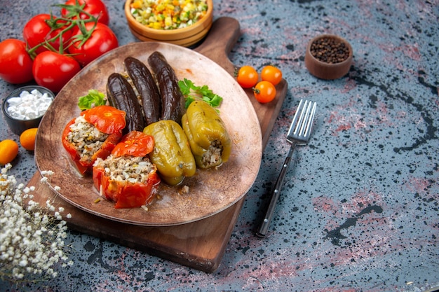 Vorderansicht köstliche Gemüsedolma mit Salat und Tomaten auf blauem Hintergrund