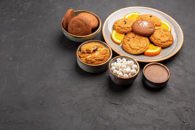 Vorderansicht köstliche Kekse mit frisch geschnittenen Orangen auf dunklem Boden Keks Obst süßer Kuchen Keks Zitrus