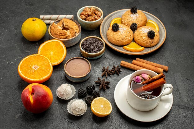 Vorderansicht köstliche Kekse mit Tasse Tee und Orangenscheiben auf dunklem Hintergrund Teetorte Keks Kekskuchen