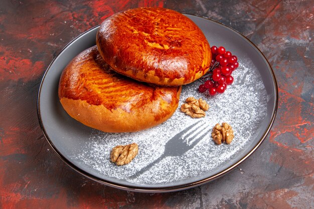 Vorderansicht köstliche Kuchen mit roten Beeren auf dunklem Tisch süßer Gebäckkuchen-Kuchen