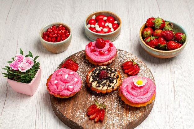 Vorderansicht köstliche Obstkuchen cremige Desserts mit Früchten auf weißem Hintergrund Sahneplätzchen-Dessert süßer Kuchentee