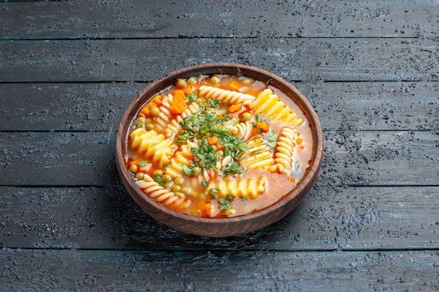 Vorderansicht köstliche Pastasuppe aus spiralförmiger italienischer Pasta mit Grüns auf dem dunklen Schreibtischgericht italienische Pastasuppe Abendessen Sauce