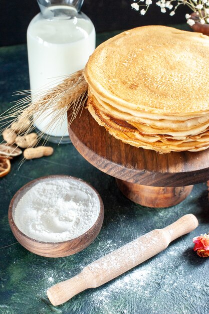 Vorderansicht köstliche Pfannkuchen mit Milch auf dunkelblauem Dessertfrühstück Honigmilch süßer Morgenkuchen