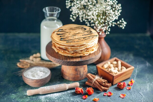 Vorderansicht köstliche Pfannkuchen mit Milch und Nüssen auf dunkelblauem Milchdessert Frühstück Honig süßer Morgenkuchen