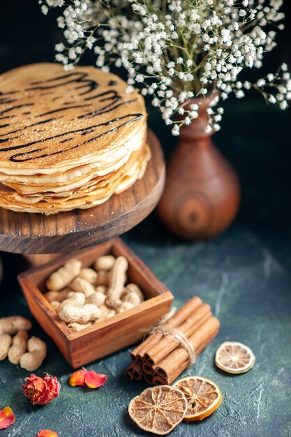 Vorderansicht köstliche Pfannkuchen mit Nüssen auf dem dunkelblauen Milchdessert süßer Morgenkuchenkuchen Honigfrühstück