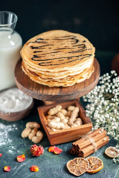 Vorderansicht köstliche Pfannkuchen mit Nüssen auf dunkelblauem Kuchen Milchdessert süßer Morgenkuchen Honigfrühstück