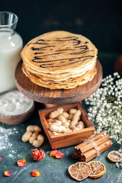 Vorderansicht köstliche Pfannkuchen mit Nüssen auf dunkelblauem Kuchen Milchdessert süßer Morgenkuchen Honigfrühstück