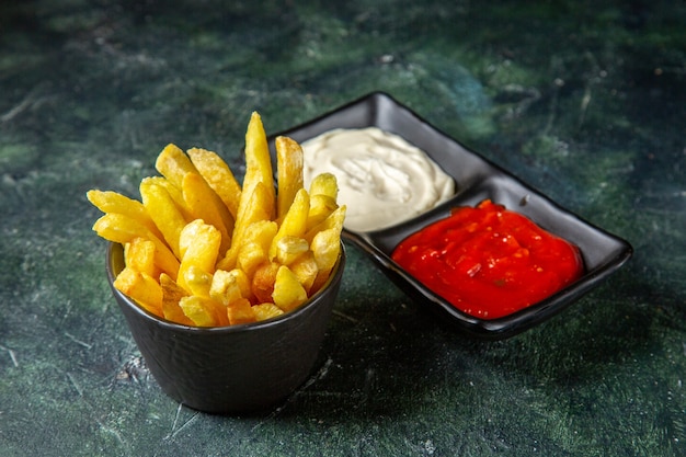 Vorderansicht köstliche Pommes Frites mit Gewürzen auf dunkler Oberfläche