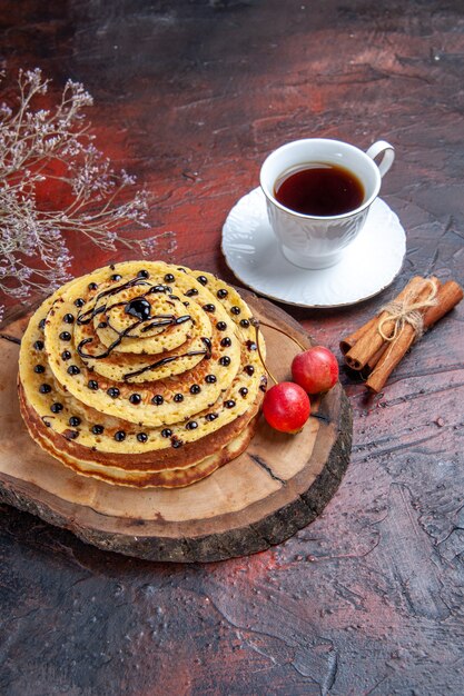 Vorderansicht köstliche süße Pfannkuchen mit Tasse Tee auf dem dunklen Hintergrund