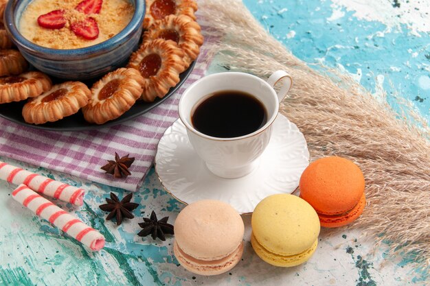 Vorderansicht köstliche Zuckerkekse mit Macarons Tasse Kaffee und Erdbeerdessert auf blauem Oberflächenplätzchenkeks süßer Nachtischzuckerkuchen