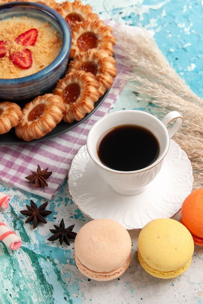 Vorderansicht köstliche Zuckerkekse mit Macarons Tasse Kaffee und Erdbeerdessert auf dem blauen Schreibtischkekskeks süßer Nachtischzuckerkuchen