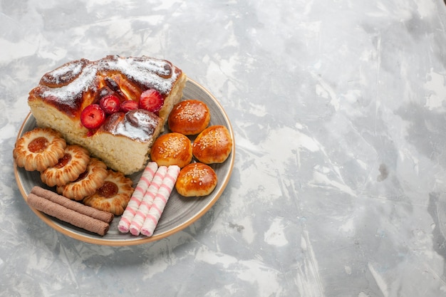 Vorderansicht köstlicher Erdbeerkuchen mit Keksen und kleinen Kuchen auf der weißen Oberfläche