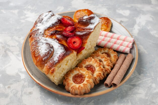 Vorderansicht köstlicher Erdbeerkuchen mit Keksen und kleinen Kuchen auf weißem Schreibtisch