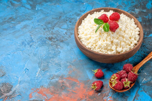 Vorderansicht köstlicher Hüttenkäse mit frischen Himbeeren auf blauem Hintergrund Gesundheit weiße Farbe Beerenfoto Milchfrucht