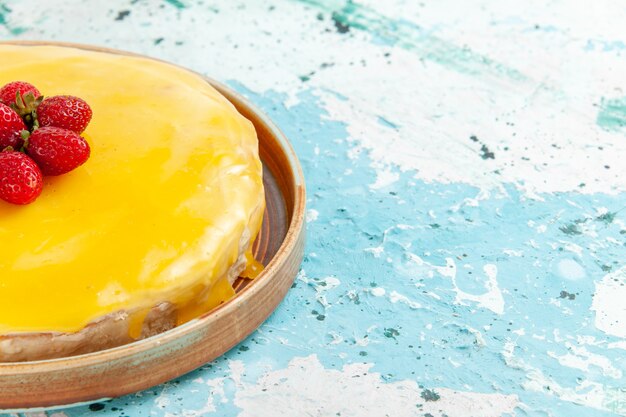 Vorderansicht köstlicher Kuchen mit gelbem Sirup und frischen roten Erdbeeren auf hellblauer Oberfläche