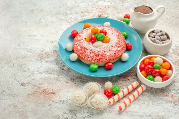 Vorderansicht köstlicher rosa Kuchen mit bunten Bonbons auf weißem Hintergrund Dessertfarbe Regenbogen Süßigkeiten Kuchen Goodie