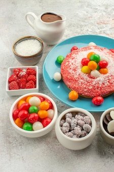 Vorderansicht köstlicher rosa kuchen mit bunten bonbons auf weißem hintergrund farbe dessert keks süßigkeiten kuchen regenbogen