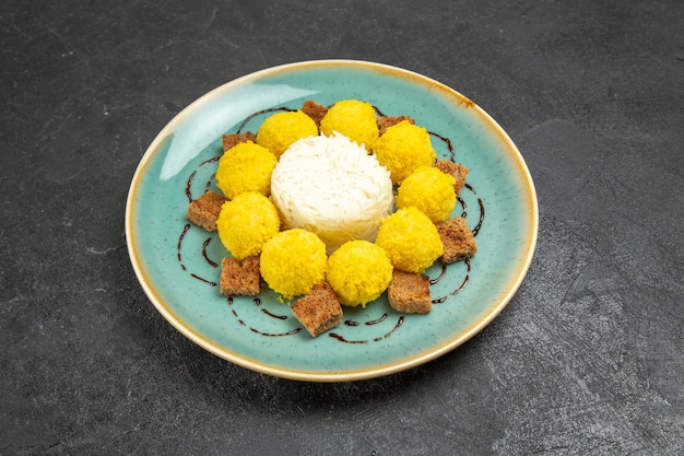 Kostenloses Foto vorderansicht köstliches dessert kleine gelbe bonbons mit kuchen in der platte auf dem grauen hintergrund süßigkeiten tee zuckerkuchen süß