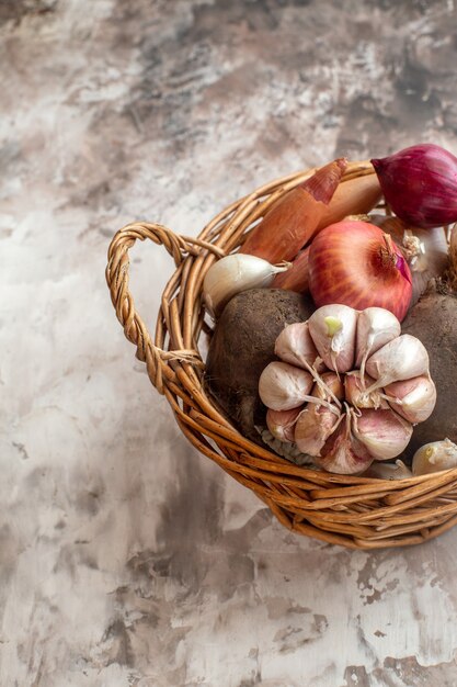 Vorderansicht-Korb mit Gemüse, Knoblauch, Zwiebeln und Rüben auf hellem Hintergrund